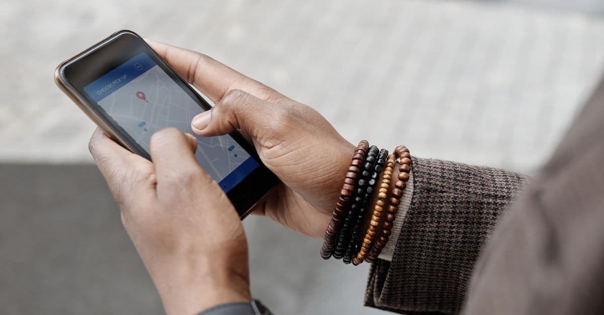 Close-up of hands with bracelets navigating on smartphone using GPS app outdoors.