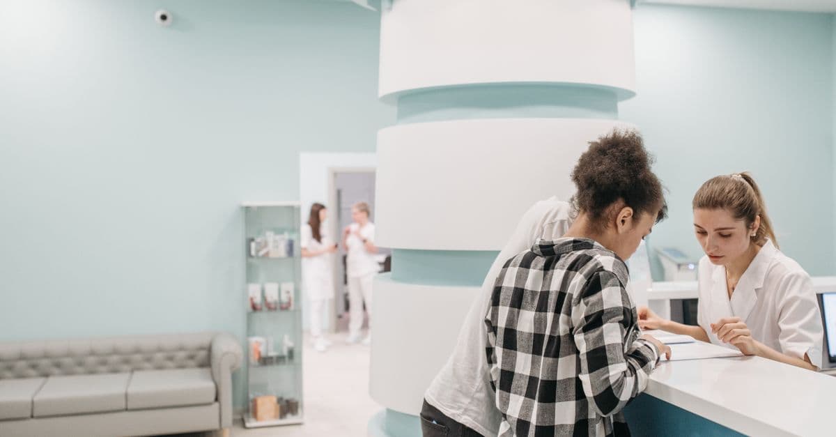Healthcare professionals assisting at a modern clinic reception desk.