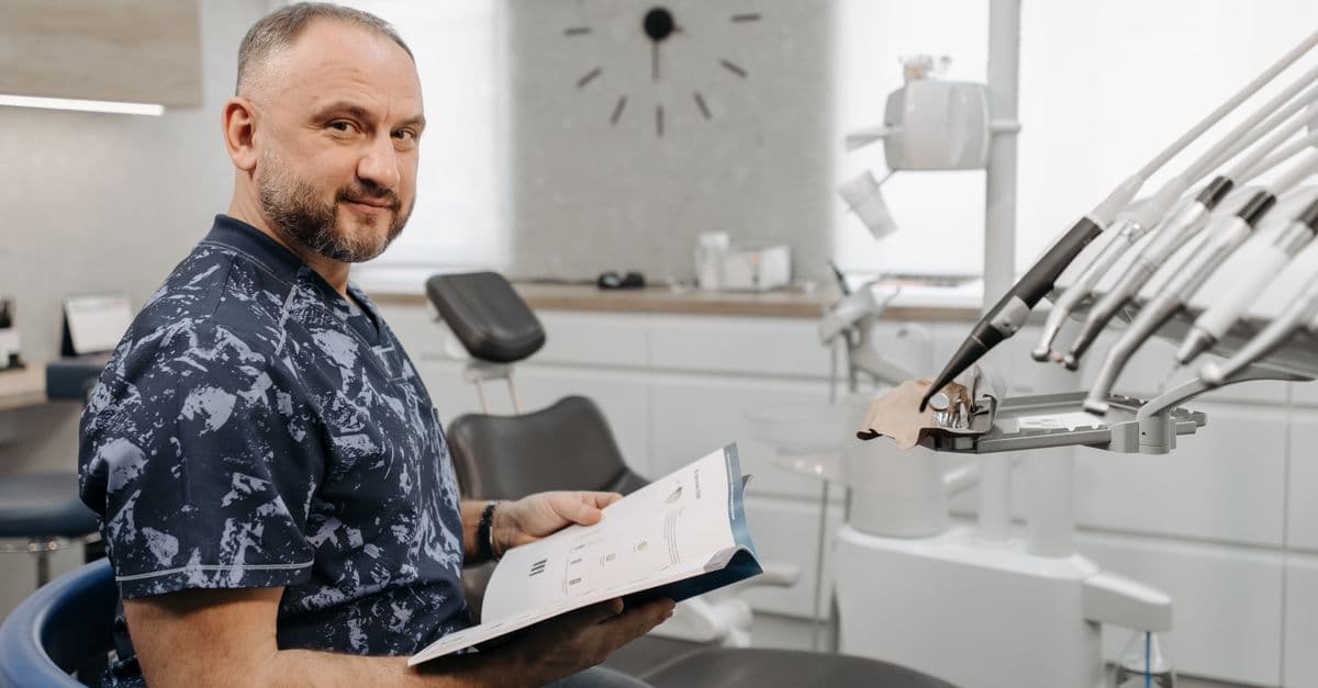 A dentist reviews patient records in a modern dental clinic setting.