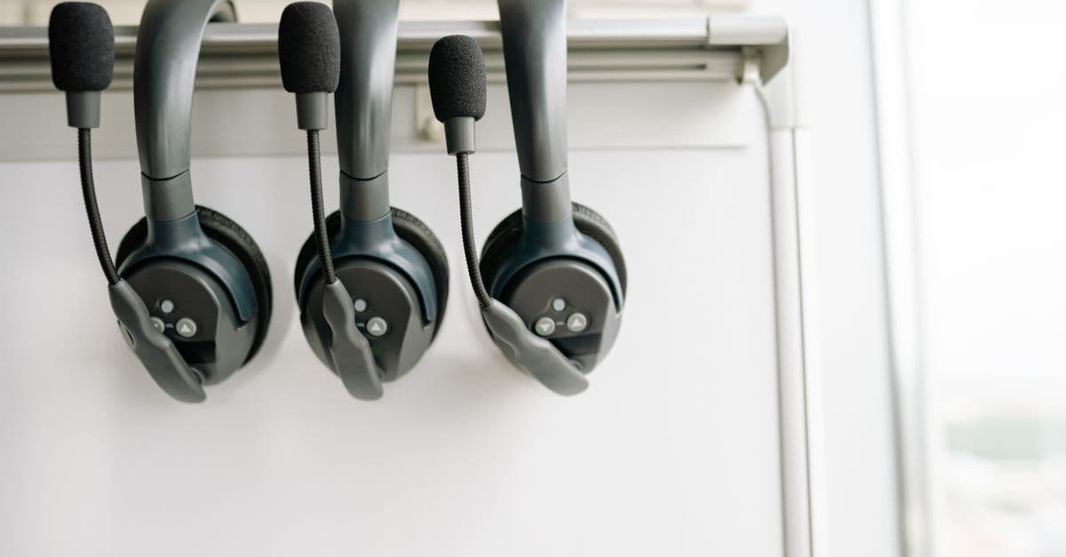 Three black headsets neatly organized on a whiteboard hook, emphasizing tech and communication.