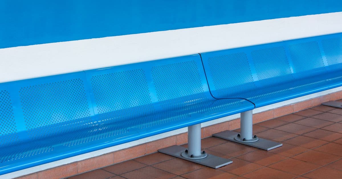 Sleek metallic blue bench in a bright, empty waiting room, highlighting minimalist design.